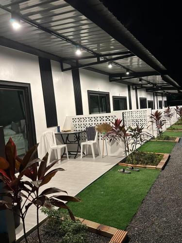 a patio with white chairs and a table and grass at Da Airport Hotel in Nai Yang Beach