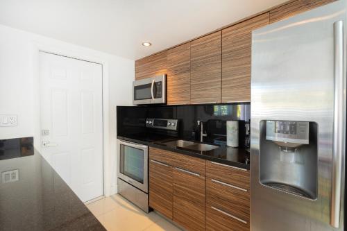 a kitchen with wooden cabinets and a stainless steel refrigerator at GroveO5 10 minutes from Miami Beach in Miami