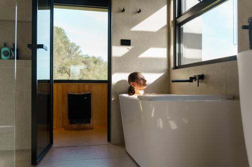 una donna seduta in bagno in una vasca da bagno di AUTRA Resort Lyndoch a Lyndoch