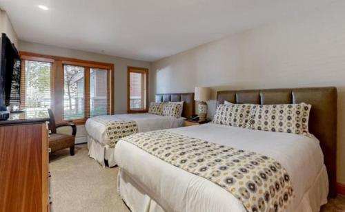 a bedroom with two beds and a flat screen tv at Luxury Ski In, Ski Out 2 Bedroom Mountain Residence In The Heart Of Lionshead Village With Heated Slope Side Pool And Hot Tub in Vail