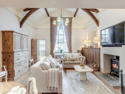 Una sala de estar con muebles blancos y un televisor. en The School Room, en Dymock