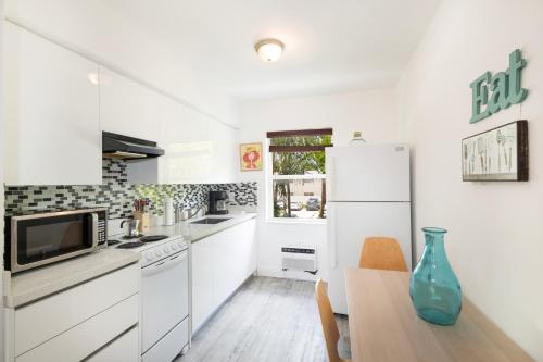 a white kitchen with a table and a refrigerator at The Oasis in Miami