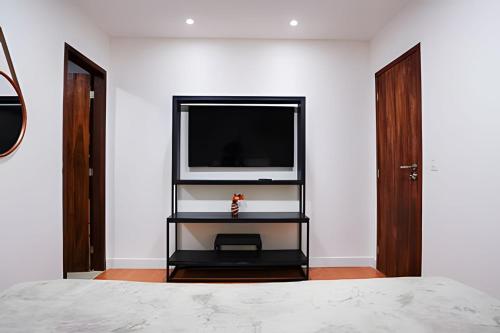 - une chambre dotée d'une télévision sur un mur blanc dans l'établissement Flat Exclusivo com Piscina Privativa e Vista Incrível, à Fernando de Noronha