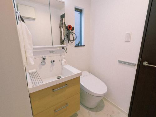 a bathroom with a sink and a toilet and a mirror at Han Homes Yokohama in Yokohama