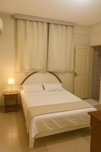 a bedroom with a large white bed with a window at Hotel Lídia in Fortaleza