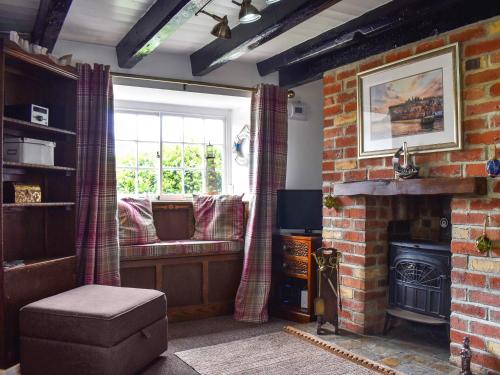 a living room with a brick fireplace and a window at White Cottages in Whitby