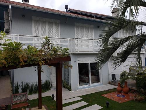 a white house with a palm tree in front of it at Casa dos Vinhedos, Conforto, Lazer e Eventos em Bento Gonçalves in Bento Gonçalves
