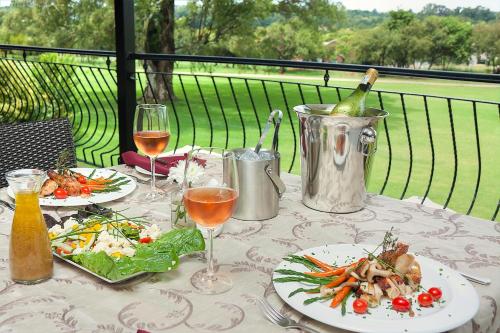 a table with two plates of food and a bottle of wine at Leopardsong Manor in Centurion