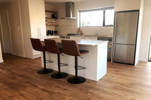 a kitchen with a white counter and two stools at Hot Tub and Views in Castle Hill