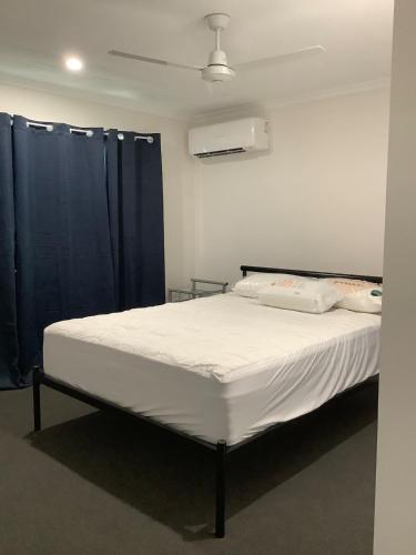 a bedroom with a large bed with blue curtains at Quiet, Cool & Modern 3BR in Moranbah