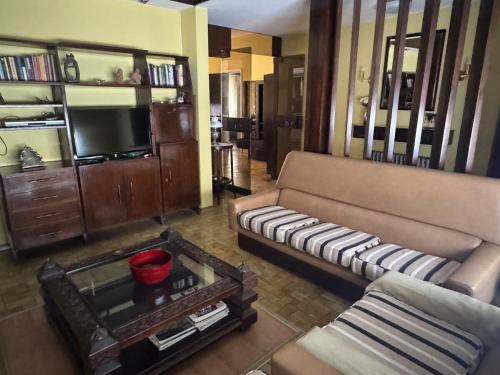 Una sala de estar con un sofá y un televisor. en La Casona, en Alta Gracia