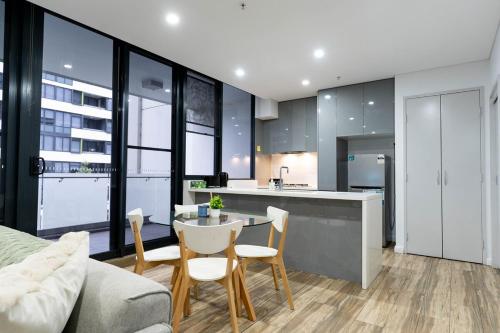 a kitchen and living room with a table and chairs at Luxe Sydney Olympic Park Stay - 2BR for 4 Guest in Sydney