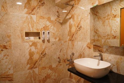 baño con lavabo en una pared de mármol en Aldea Retreat Resort, en Kūvattūr