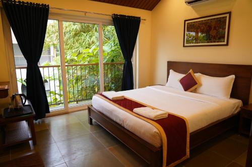 Un dormitorio con una cama y una ventana grande. en Aldea Retreat Resort, en Kūvattūr