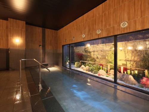 a swimming pool in a building with a large aquarium at Hotel Route Inn Suzaka in Suzaka