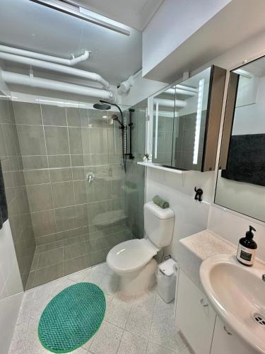 a bathroom with a toilet and a shower and a sink at West End Central Apartments in Brisbane