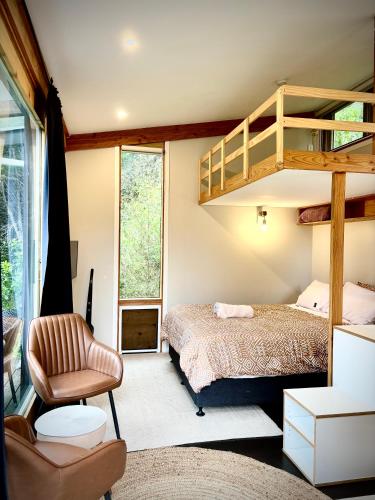 a bedroom with a bunk bed and a chair at Fantail’s Nest in the forest in Takaka