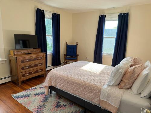 a bedroom with a bed and a dresser and a television at Seaside Stay in Historic Warren in Warren