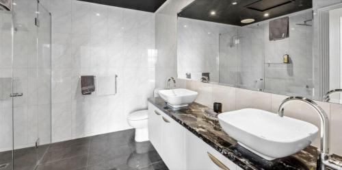 a white bathroom with a sink and a toilet at PENTHOUSE at OZONE in Queenscliff
