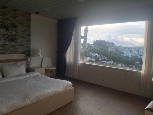 a bedroom with a bed and a large window at Đối diện cafe CATINAT villa Kagen in Da Lat