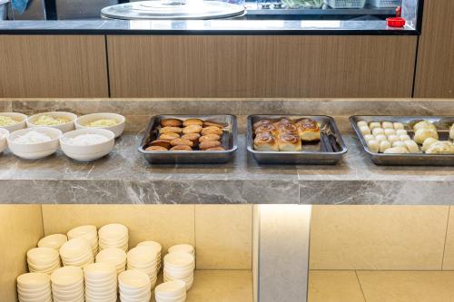 Un mostrador con bandejas de diferentes tipos de donas. en Li Cheng Hotel, en Kunming
