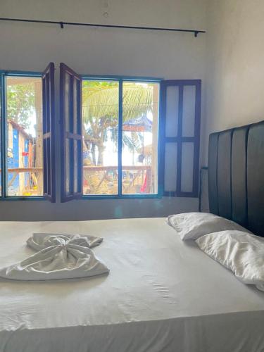 a bed with a napkin on it with two windows at Hostel casa jungla in Palomino