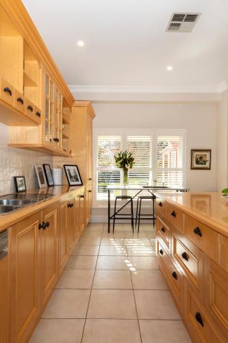 a kitchen with wooden cabinets and a table with a vase of flowers at 23onWindsor in Hahndorf