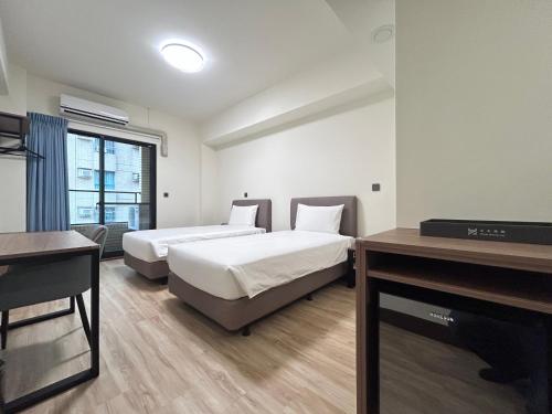ein Hotelzimmer mit zwei Betten und einem Fernseher in der Unterkunft 水木商旅高鐵左營館 in Nan-men