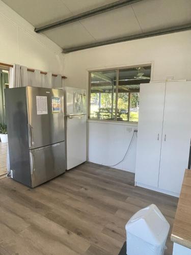 a kitchen with a stainless steel refrigerator and white cabinets at Orchid Oasis Orchid Beach KGari Fraser Island in K'gari Island (Fraser Island)