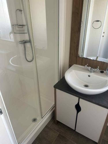 a bathroom with a white sink and a shower at Newton Beach retreat in Porthcawl