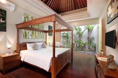 a bedroom with a canopy bed and a large window at Villa J Deluxe in Canggu