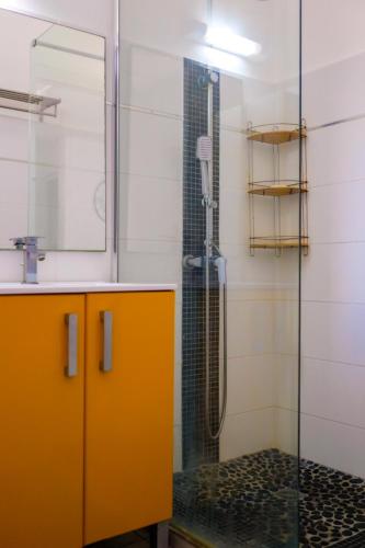 a bathroom with a shower with an orange cabinet and a sink at chez marvin in Pointe-à-Pitre
