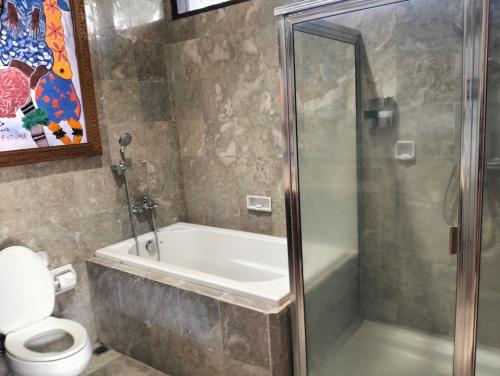 a bathroom with a shower and a tub and a toilet at Villa Biyu siyu in Ubud