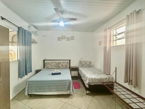 a room with two beds and a ceiling fan at Pousada e Hotel Italian Garden House in Campo Grande