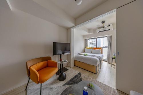 a bedroom with a bed and a chair and a television at Daffitto Oshiage I in Tokyo