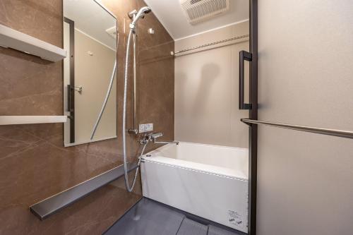 a bathroom with a shower and a tub and a mirror at Daffitto Oshiage I in Tokyo