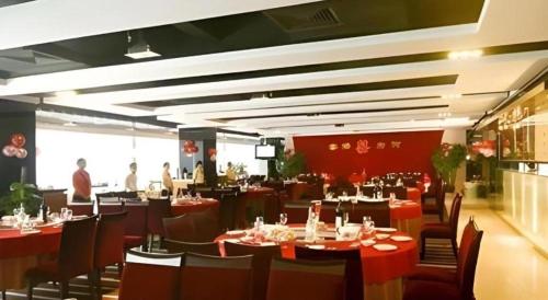 ShenzhenにあるOrient Sunseed Hotel Airport Branchのテーブルと椅子、背景の人々が並ぶレストラン