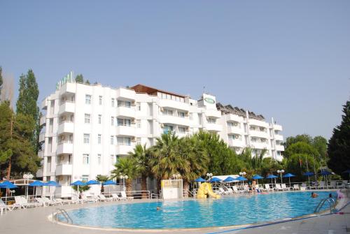 a hotel with a swimming pool in front of a building at Hotel Flora Suites - All Inclusive in Kuşadası