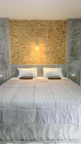 a bedroom with a large white bed with a wooden wall at Lanta Miss House in Ko Lanta
