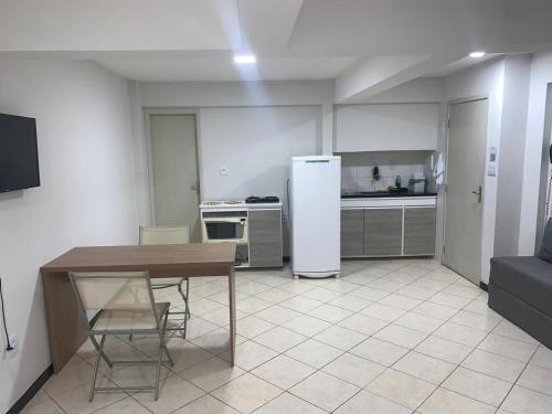 a kitchen with a table and a refrigerator at Studio amplo e aconchegante no bairro aterrado in Volta Redonda