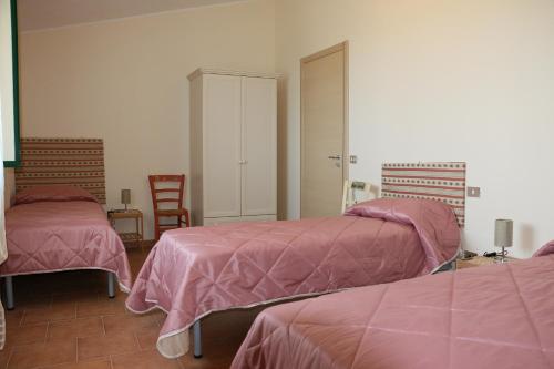 1 dormitorio con 2 camas con sábanas rosas y espejo en B&B Il Vigneto, en Trebisacce