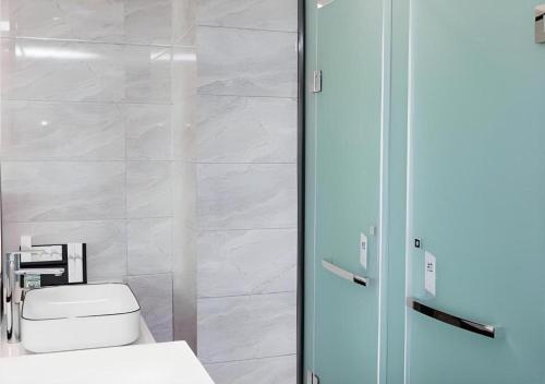 une salle de bain avec toilettes et douche en verre dans l'établissement Borrman Hotel East Huai'an Railway Station Zhou 'Enlai Memorial, à Hexia