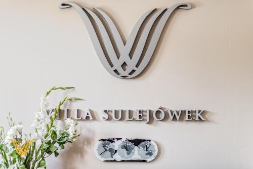 a sign for a hotel with a v sign on a wall at Villa Sulejówek in Sulejówek