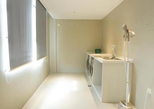 une cuisine blanche avec un évier et une machine à laver dans l'établissement City Comfort Inn Huanggang Tuanfeng Passenger, à Luotian