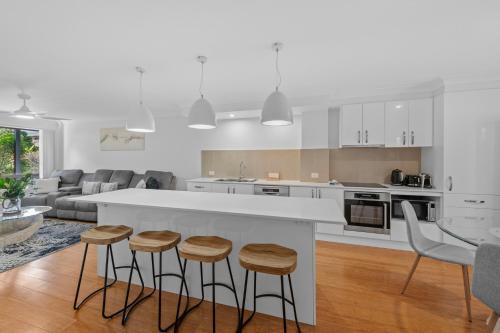 a white kitchen with a counter and stools at Hilltop Residences Chermside in Brisbane