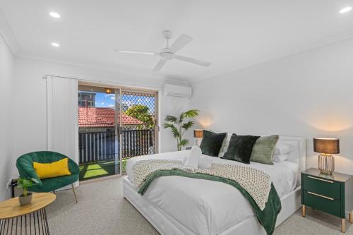 a white bedroom with a bed and a balcony at Hilltop Residences Chermside in Brisbane