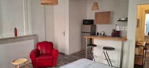 a living room with a red chair and a kitchen at Studio au cœur de Sommières in Sommières