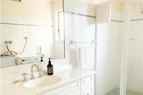 a white bathroom with a sink and a mirror at Glens Parkview Apartments in Wagga Wagga
