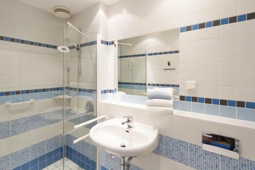 un bagno blu e bianco con lavandino e doccia di Bergkloster Bestwig a Bestwig