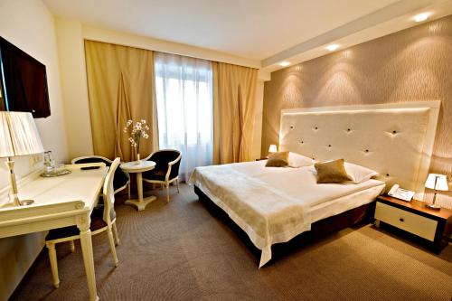 ジェシュフにあるHotel Prezydencki 4-starの大きなベッドとデスクが備わるホテルルームです。